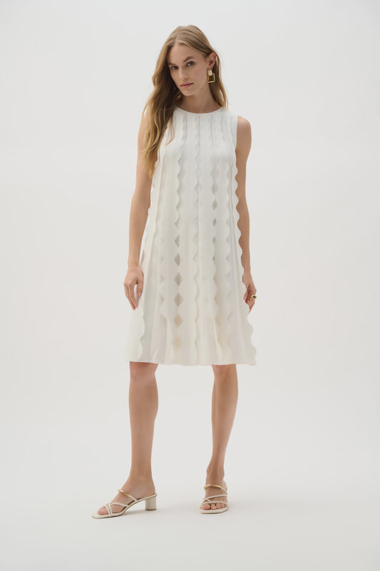 Sleeveless vanilla knit A-line dress with high crew neckline, allover 3D scallop appliqués and a back tie, above-knee length