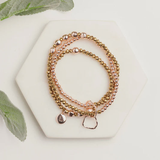 Shiny three strand stretch bracelet in silver, gold and rose gold, made from brass and alloy, shown on a plain background