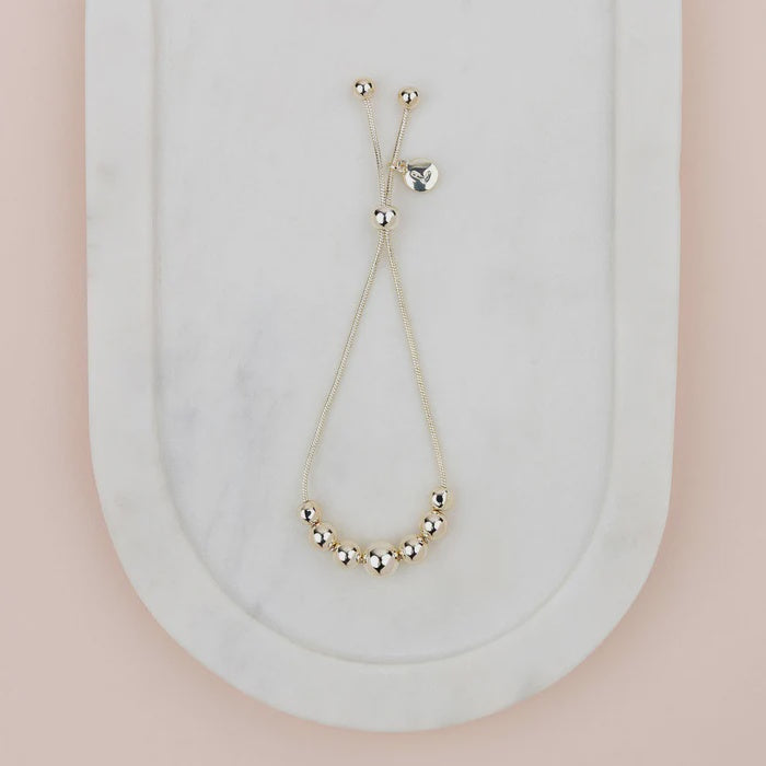 Adjustable shiny gold bracelet with a smooth, polished finish, shown as a round open-style cuff