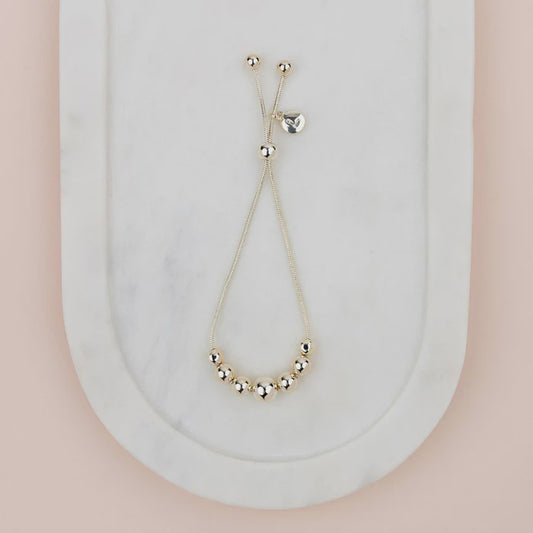 Adjustable shiny gold bracelet with a smooth, polished finish, shown as a round open-style cuff