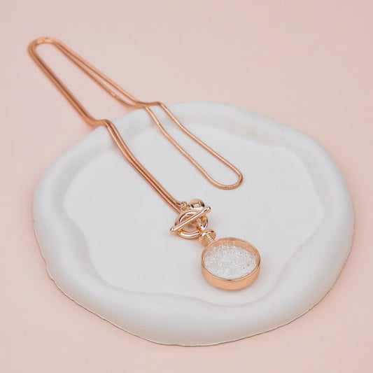 Rose gold necklace with a small crystal pendant on a long, sleek snake chain with a lobster clasp