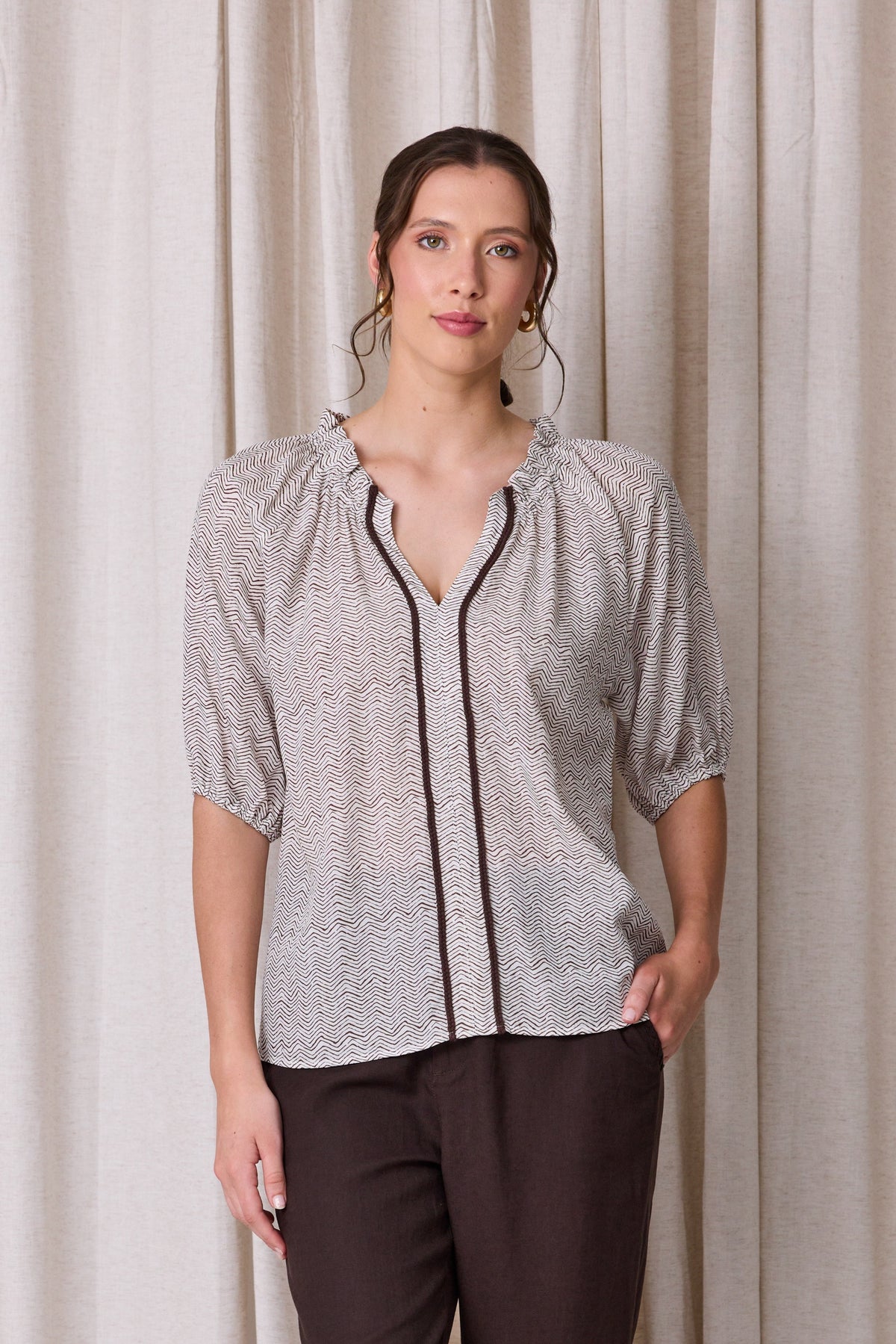 Pale grey and white zigzag print blouse with raglan sleeves, three-quarter elastic cuffs and a cocoa brown contrast trim down the front