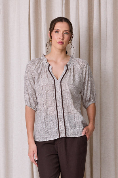 Pale grey and white zigzag print blouse with raglan sleeves, three-quarter elastic cuffs and a cocoa brown contrast trim down the front
