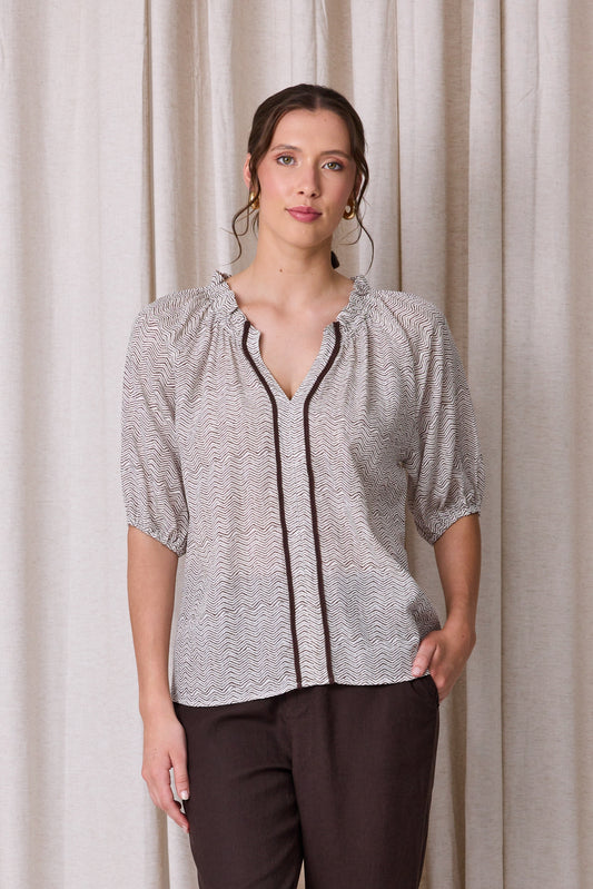 Pale grey and white zigzag print blouse with raglan sleeves, three-quarter elastic cuffs and a cocoa brown contrast trim down the front