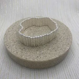 Silver multi-line stretch bracelet with several polished, interwoven strands, shown as a stacked band by Fabienne