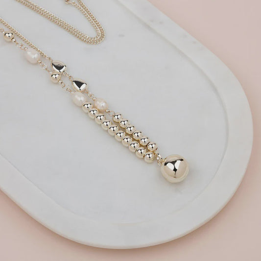Long gold-tone necklace with freshwater pearls and gold beads threaded along a pretty chain with a small pendant